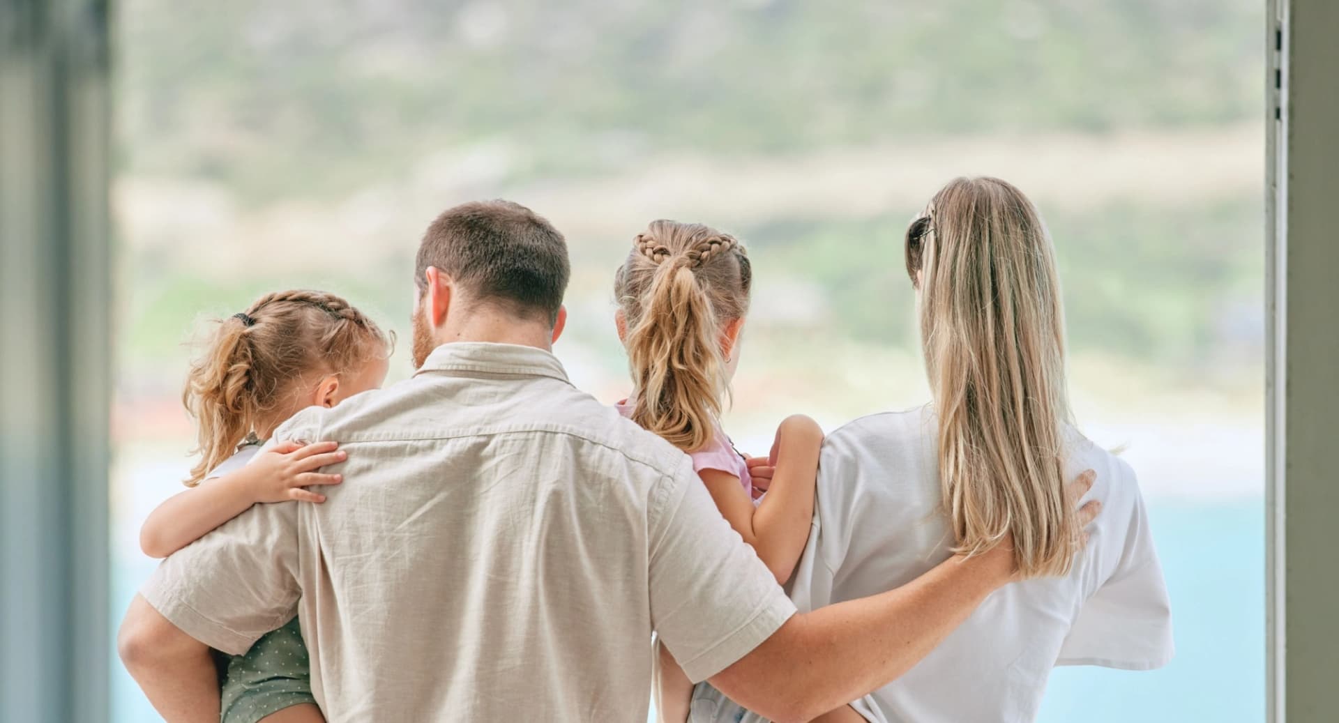 Family of four hugging while looking out the window